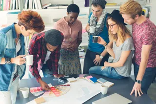Diverse group of young adults collaborating over design samples in a creative office environment.