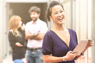 Woman using tablet with people talking in the background