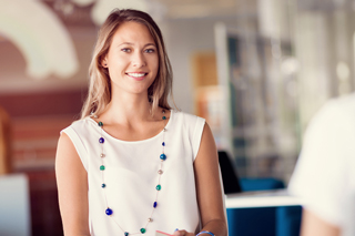 Businesswoman in an office wearing a white blouse and colorful necklace