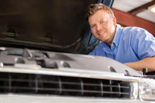 Male mechanic checking car engine in workshop