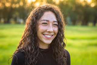 Young woman with curly hair smiling in a sunlit park