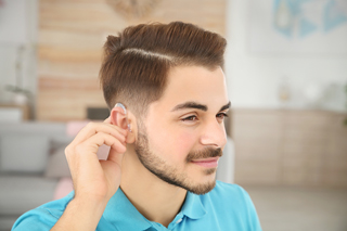 Man at home adjusting his hearing aid