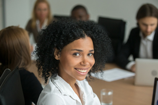 Young woman with curly hair at a business meeting with colleagues in the background
