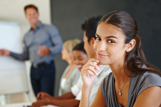 Young woman smiling in a classroom setting with other students and a male instructor in the background
