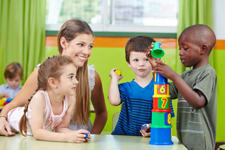 Teacher and diverse group of preschool children playing with colorful stacking cups in classroom