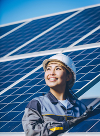 Asian female engineer in hard hat checking solar panels with clipboard, sunny day.