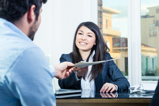 Female professional handing a document to a male client in an office setting