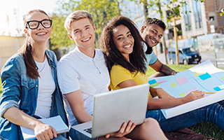 College students sitting outside with laptops