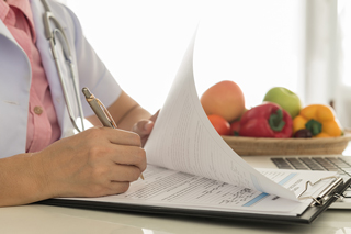 Close-up of a healthcare professional reviewing medical documents with a bowl of fresh fruits in the background, emphasizing healthy lifestyle choices.