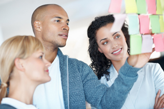 Three colleagues collaborating with sticky notes in a creative office setting