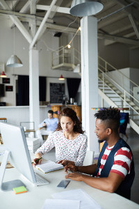 Two professionals collaborating at a computer in an office space
