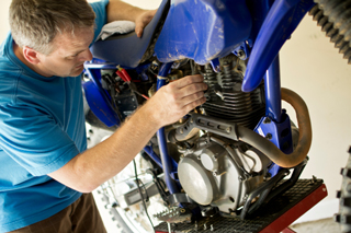 Man repairing a motorcycle engine in a workshop