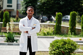 Doctor in a white coat standing outdoors with arms crossed