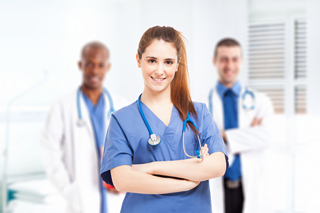 Nursing student with a stethoscope around her neck in a hospital setting with two colleagues in the background.
