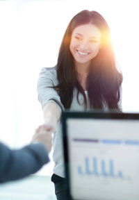 Office administrator smiling while shaking hands in an office setting.