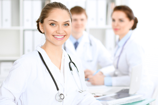 Three medical professionals in a hospital office, featuring a Doctor in the foreground with a stethoscope around her neck and two colleagues working in the background.