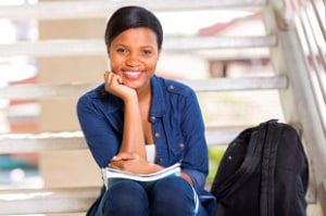 A female student sitting on steps with a backpack