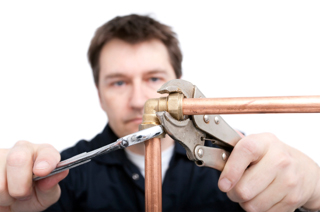 Plumber soldering copper pipe with focused expression using a propane torch and pliers, isolated on white background
