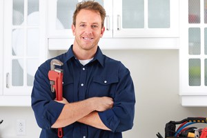 A smiling plumber holding a wrench