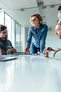 Public relations manager leading a meeting with three colleagues in an office.