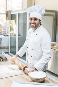 Smiling chef rolling out dough