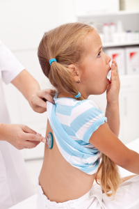Young girl getting a checkup and respiratory therapist listens to her lungs with a stethoscope