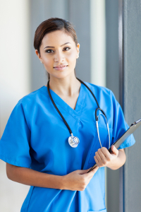 RN in blue scrubs with stethoscope holding a clipboard