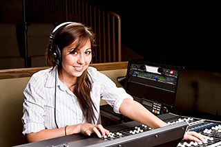 Young woman sound engineer working with audio mixing console in recording studio