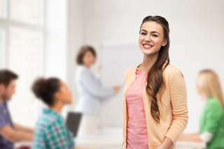 Young woman smiling in classroom with peers and teacher in background