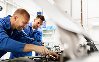 Two male mechanics working together on a car engine in an auto repair shop