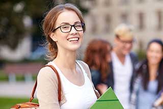 Smiling college student holding books on campus.