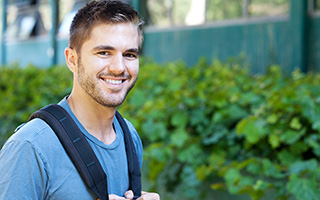 Young man with backpack smiling outdoors