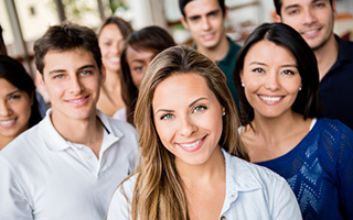 Group of diverse young adults smiling and looking at the camera, outdoors.