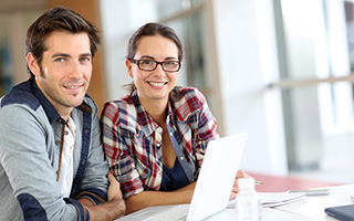 Two smiling professionals using a laptop in a bright office setting