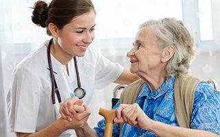Doctor caring for elderly woman with a cane in a medical office, representing a caring interaction in healthcare.
