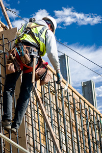 Construction worker wearing safety gear installing rebar at a construction site with blue sky in the background