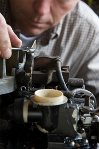 Close-up of a man repairing small engine.
