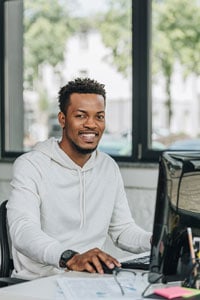 Software developer working at desk with computer in a bright office setting.