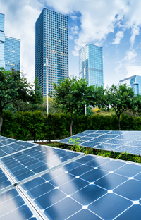 Solar panels in a city park with modern skyscrapers in the background on a sunny day.