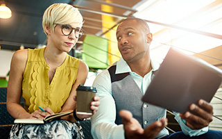 Two business professionals discussing with digital tablet in an office setting