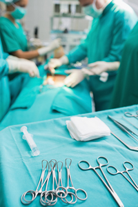 Surgeons performing operation in hospital surgery room with focus on surgical instruments and sterile equipment on foreground table