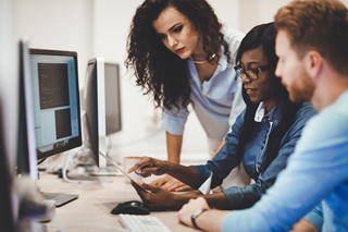 Three professionals collaborating at a computer in an office setting.