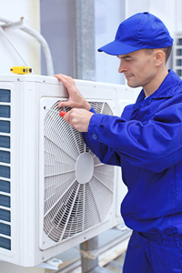 HVAC technician in blue uniform repairing an outdoor air conditioning unit