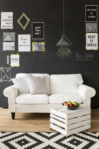 Stylish living room with white sofa, black chalkboard wall with decorative frames and notes, and geometric pattern rug