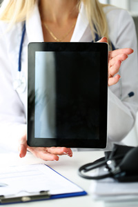 Medical professional holding a blank digital tablet screen in a medical office setting