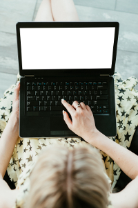 Woman in a star-patterned dress using a laptop with a blank screen outdoors